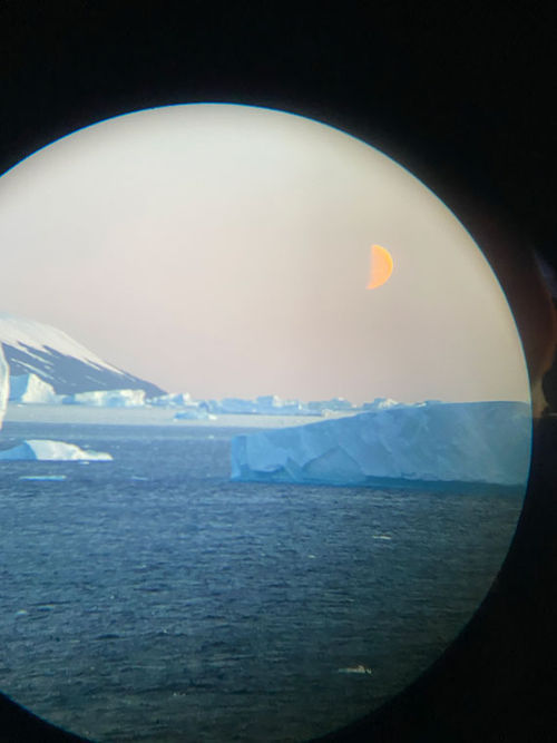 As seen through the lens of a pair of binoculars, a half-moon rises ahead of the bow of the Quark Ultramarine on its way to Antarctica. As seen through the lens of a pair of binoculars, a half-moon rises ahead of the bow of the Quark Ultramarine on its way to Antarctica.